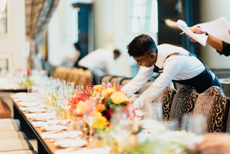 Staff members prep a banquet table. Elevate your table linens with Stamford Uniform and Linen.