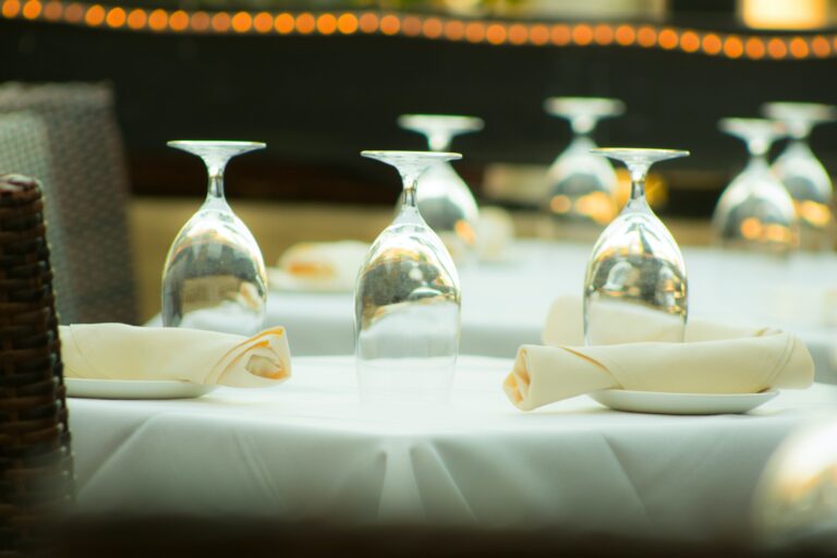 A table set with white and cream linens. Elevate your table linens with Stamford Uniform and Linen.