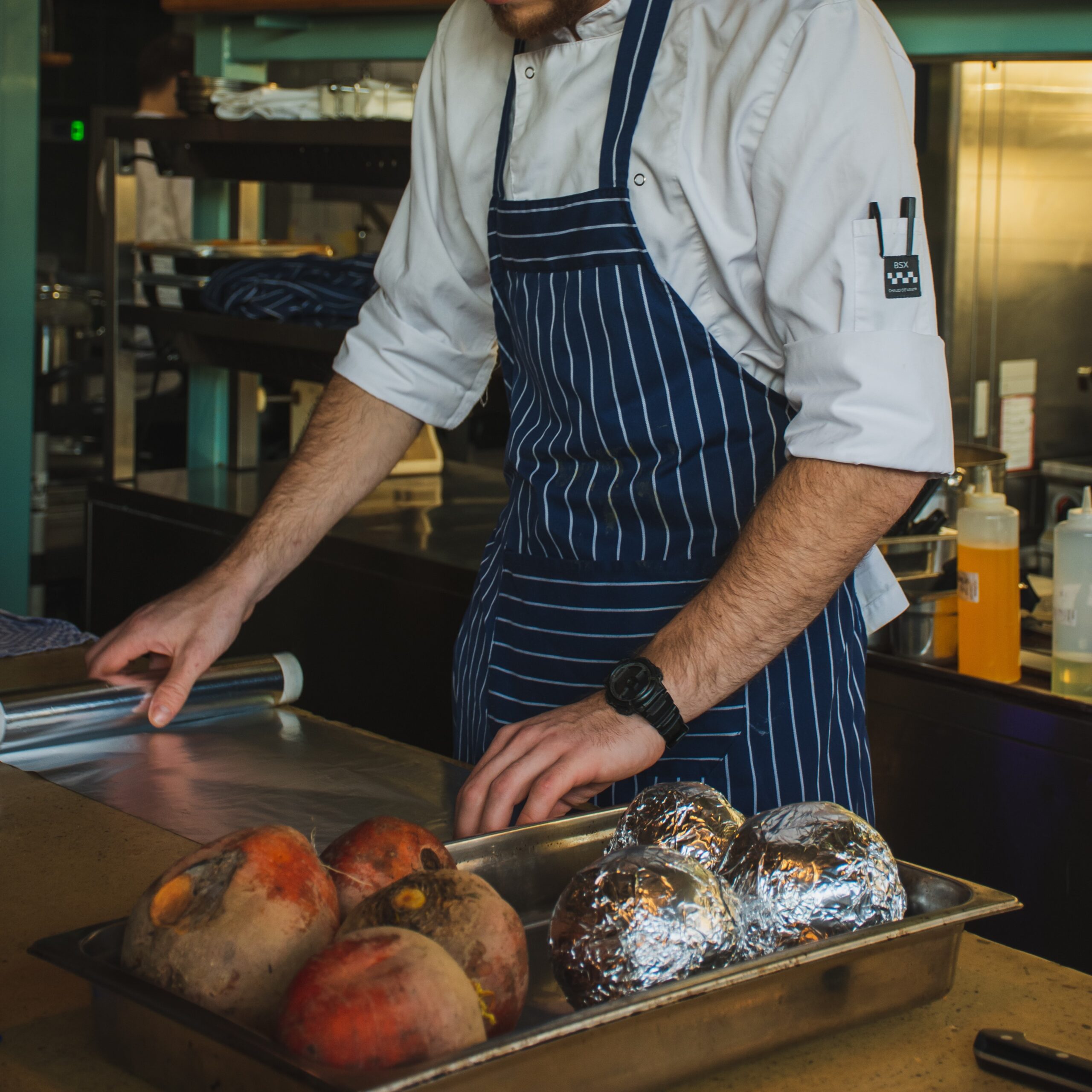 A chef in a striped apron preps food. Elevate your staff with custom uniforms from Stamford Uniform and Linen.